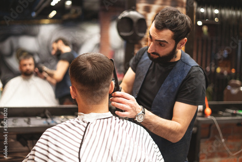 Haircut head in barbershop. Barber cuts the hair on the head of the client. The process of creating hairstyles for men. Barber shop. Selective focus.
