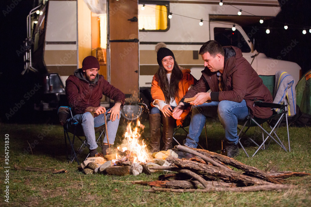 Group of friend relaxing and laughing together around camp fire Group of friend relaxing and laughing together around camp fire