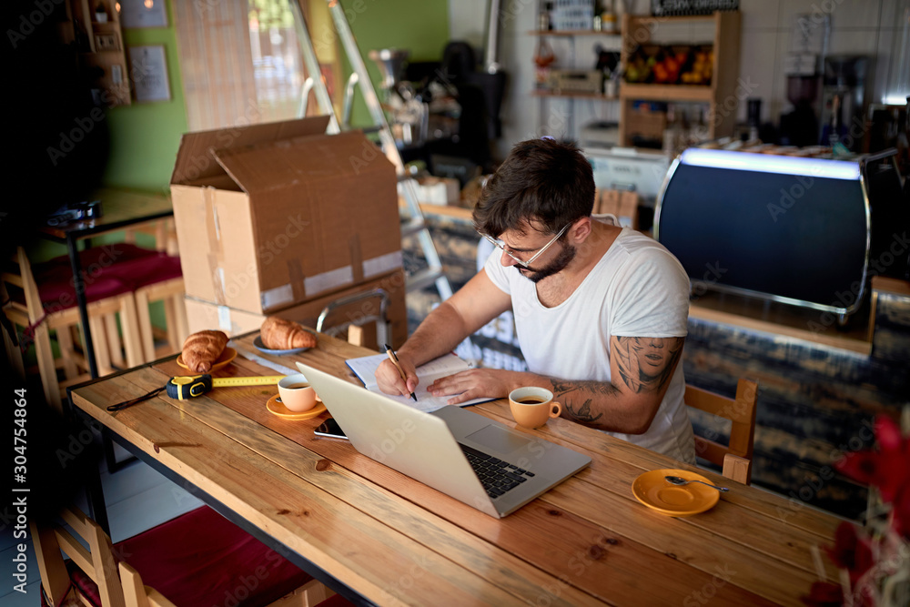 Man in coffee shop working on laptop.business owner. Man in coffee shop working on laptop.business owner.