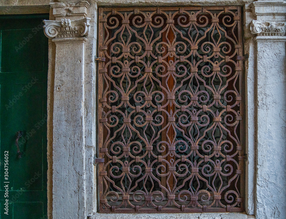 Old building in Venice, Italy. Detail of an old vintage window with rusty decorative bars. Travel inspiration.