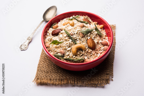 Oats Chivda / Chiwda is a healthy indian recipe with added chilli, peanuts, cashew, almond and curry leaf for flavour. Selective focus photo