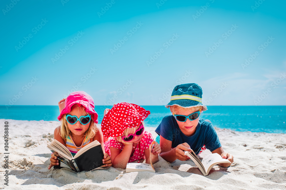 cute happy kids -boy and girls- read books on beach, family vacation