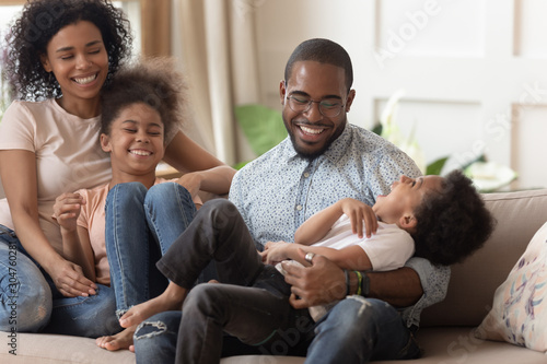 African family with little kids having fun sitting on couch