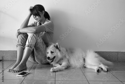 The loneliness woman sitting against the wall,,beside her dog,unhappy feeling,upset and tried,negative emotion,the Depressive disorder syndrome,black and white tone