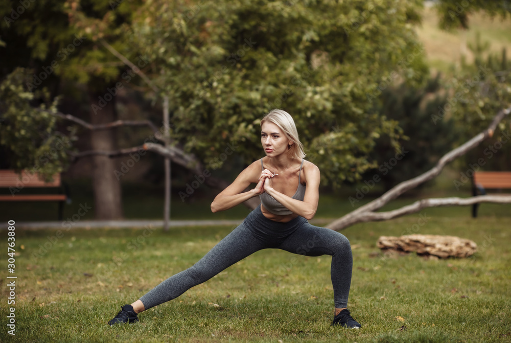 Outdoor training. Young fitness woman doing an aerobic workout before training. Warm up. stretching in the park Outdoor training. Young fitness woman doing an aerobic workout before training. Warm up. stretching in the park