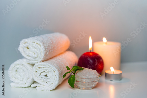 Aromatherapy and SPA session at salon photo on grey background with stack of towels, candle lights and cup of sea salt.