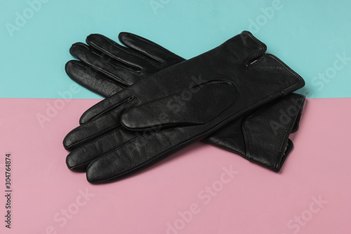 Stylish women's leather gloves on a blue-pink pastel background.