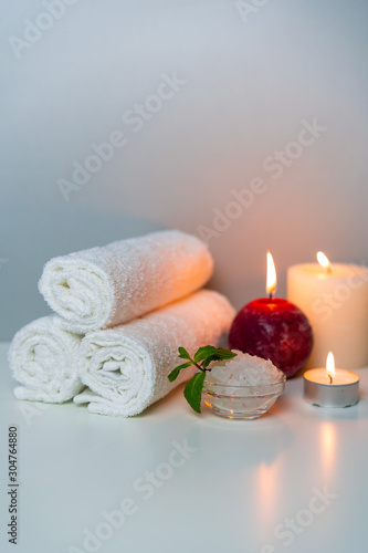 Natural health treatments of SPA, vertical orientation photo. White towels, sea salt in a cup, candles.