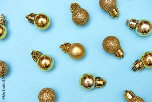 Creative Christmas pattern with golden shiny baubles on blue pastel background, copy space. Minimal, winter, new year concept. Top view, flat lay