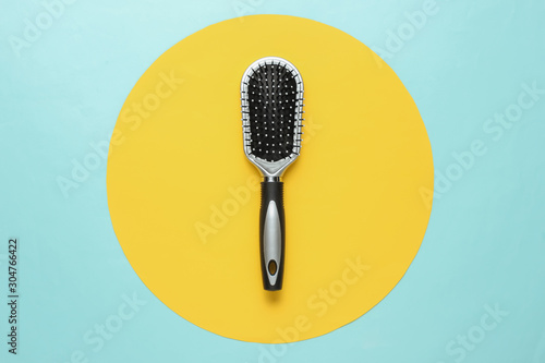 Stylish hairbrush on blue background with yellow circle. Women's Hair Care Accessories.