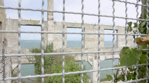 View of an old ruined building outide the bars. Alcatraz island, San Francisco California, USA. Ruins of a building covered by vegetation. Slow motion from bottom to top. photo