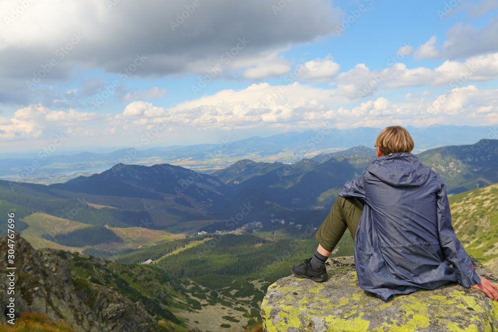Girl sitting on rock watching mountain view