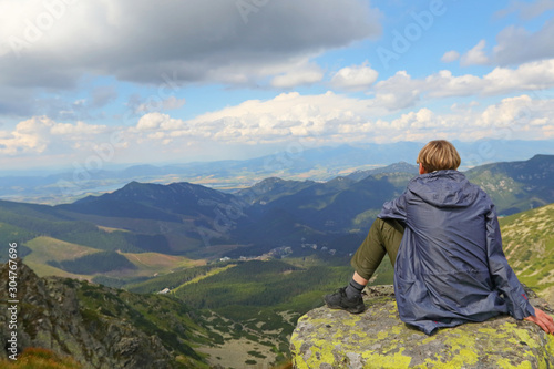 Girl sitting on rock watching mountain view