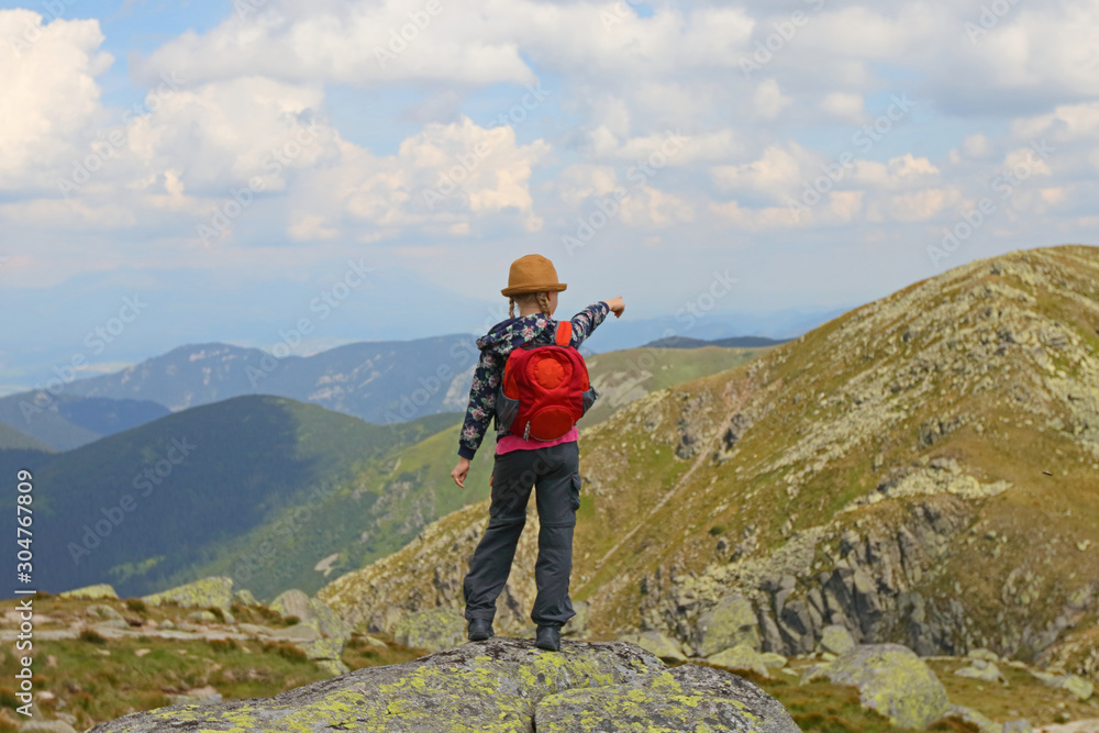 Girl standing on the hill  watching mountain view, showing the trail