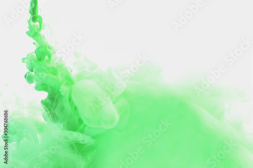 Abstract flowing liquid or green ink in water on a white background. It looks like smoke or cloud. Or zero gravity. photo