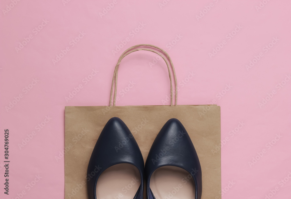Shopping concept. Fashion studio shot. Women's high-heeled shoes and paper bag for shopping on pink pastel background. Top view Shopping concept. Fashion studio shot. Women's high-heeled shoes and paper bag for shopping on pink pastel background. Top view