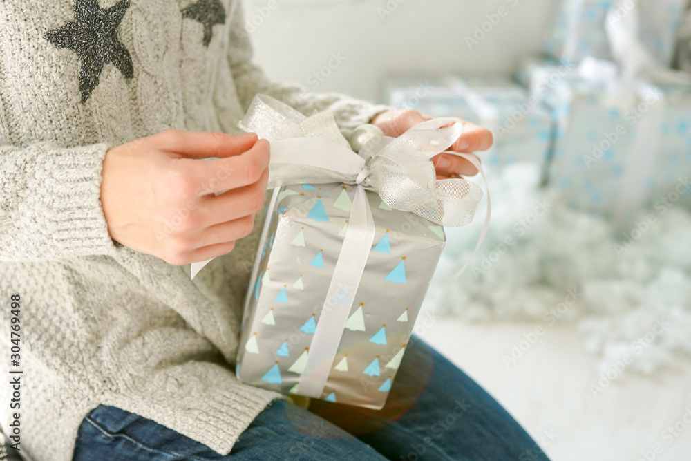 Christmas gift box in woman hands, silver celebration card