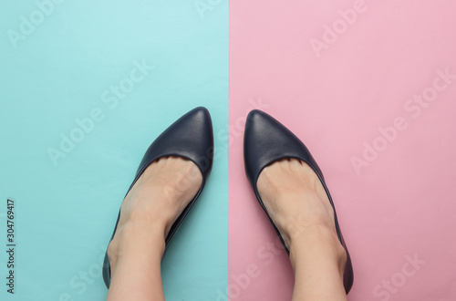Minimalism fashion concept. Female legs with leather shoes with heels on pink-blue pastel background. Top view