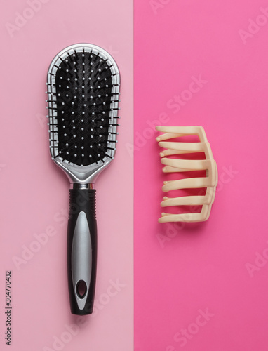 Minimalistic beauty and fashion concept. Women's hair care accessories. Comb, hair clip on pink background. Top view