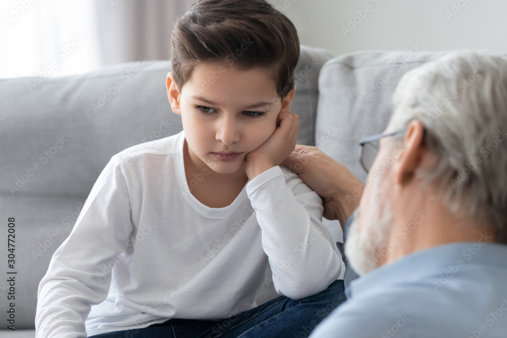 Caring grandfather calming, talking with upset little grandson Caring grandfather calming, talking with upset little grandson