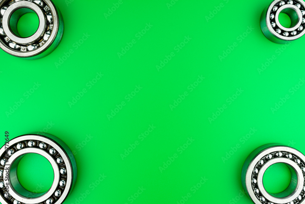 Ball bearing lying on a green background with copy space in the middle. Flat view from above. Ball bearing lying on a green background with copy space in the middle. Flat view from above.