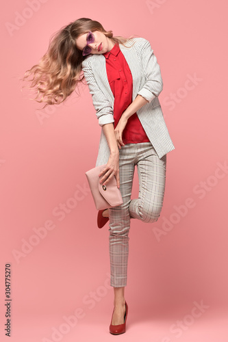 Fashionable blonde woman in Trendy elegant outfit, stylish hairstyle, makeup. Joyful funny lady in jacket dance on pink. Cheerful girl, stylish fashion accessories, beauty style, fun concept