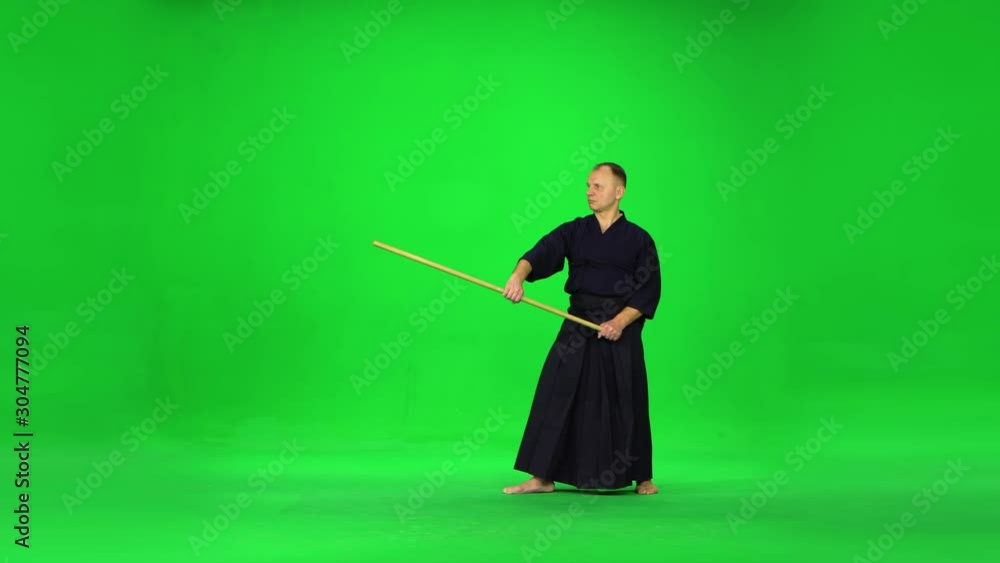 Masculine Kendo warrior practicing martial art with the bamboo bokken on green screen. Masculine Kendo warrior practicing martial art with the bamboo bokken on green screen.