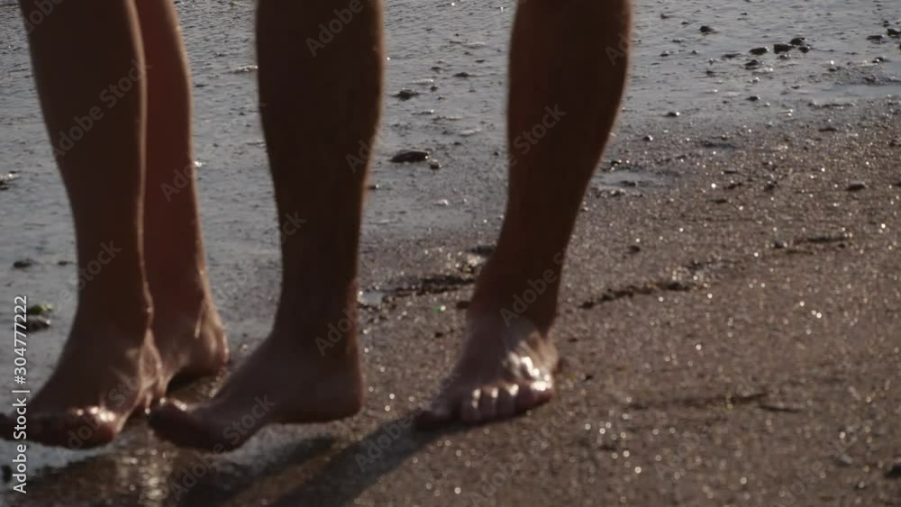 Young couple on beach at sunset, closeup. Slow motion effect Young couple on beach at sunset, closeup. Slow motion effect
