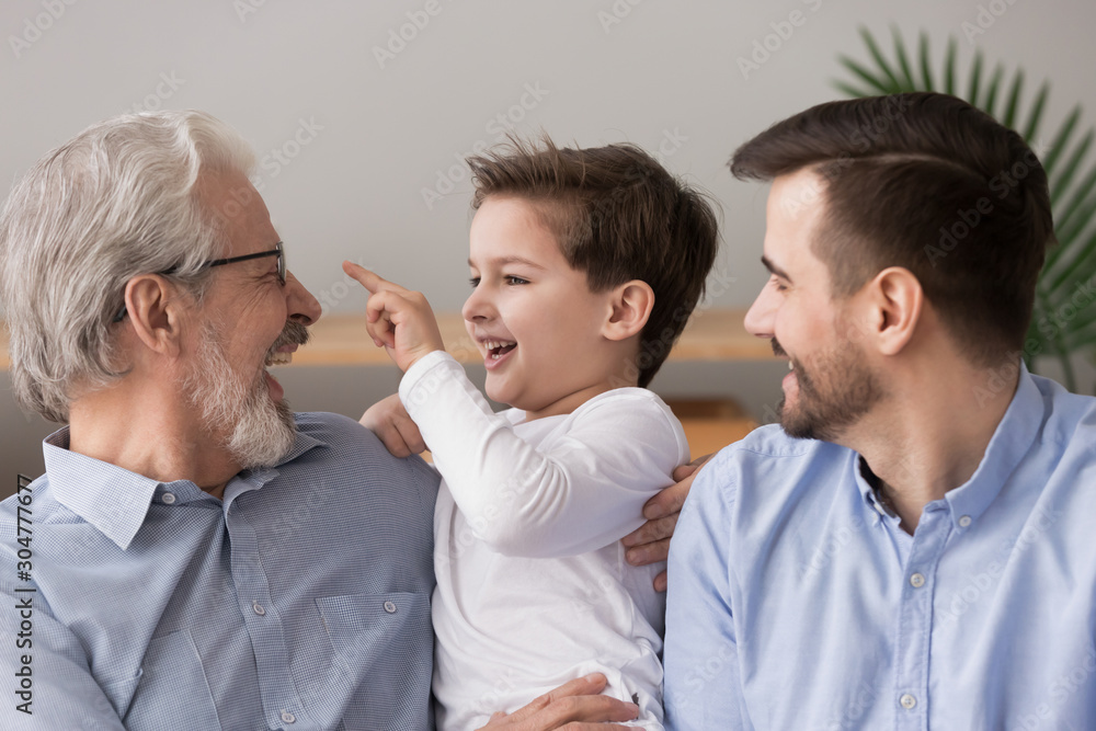 Laughing grandfather hugging grandson, three generations of men Laughing grandfather hugging grandson, three generations of men