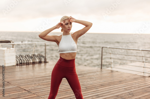 Tired young sport woman at sunrise on the beach. The concept of morning workout. Healthy lifestyle