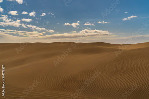 Amazing sand dunes during sunny and windy day in the Natural Reserve of Dunes of Maspaloma in Gran Canaria with sand dust  Canary Islands  Spain