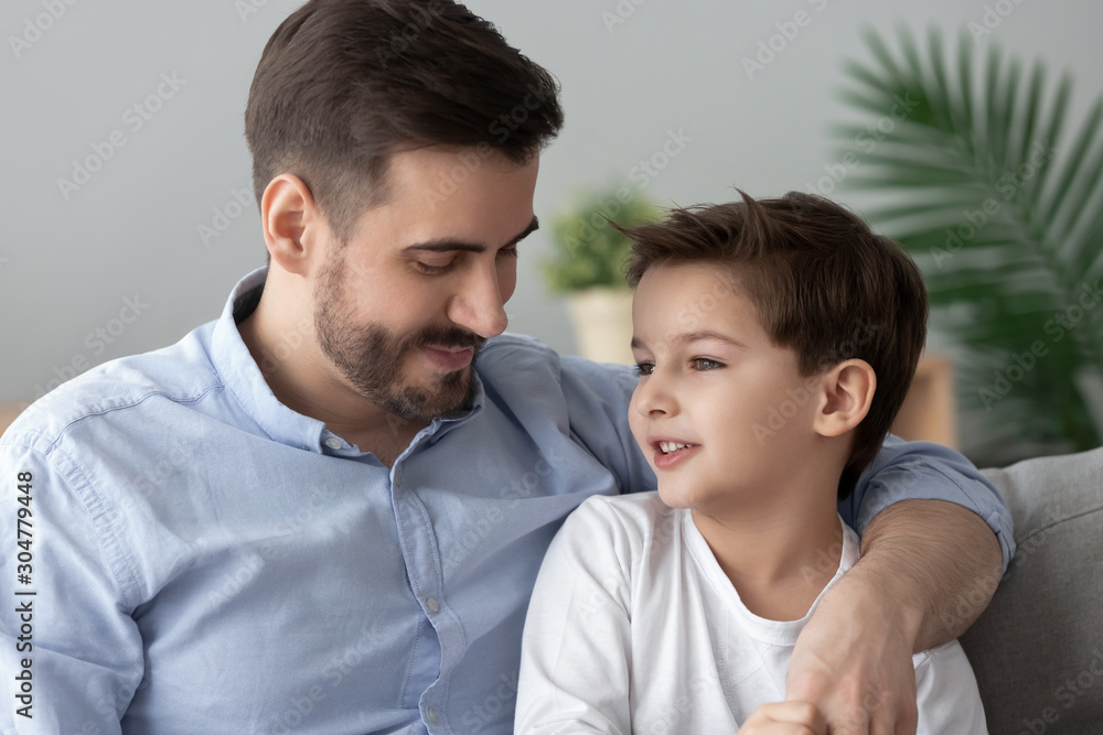 Loving father hugging, talking with little son, spending time together Loving father hugging, talking with little son, spending time together