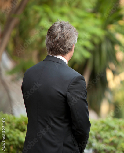 man on his back waiting with elegant suit and vivid green paradise background