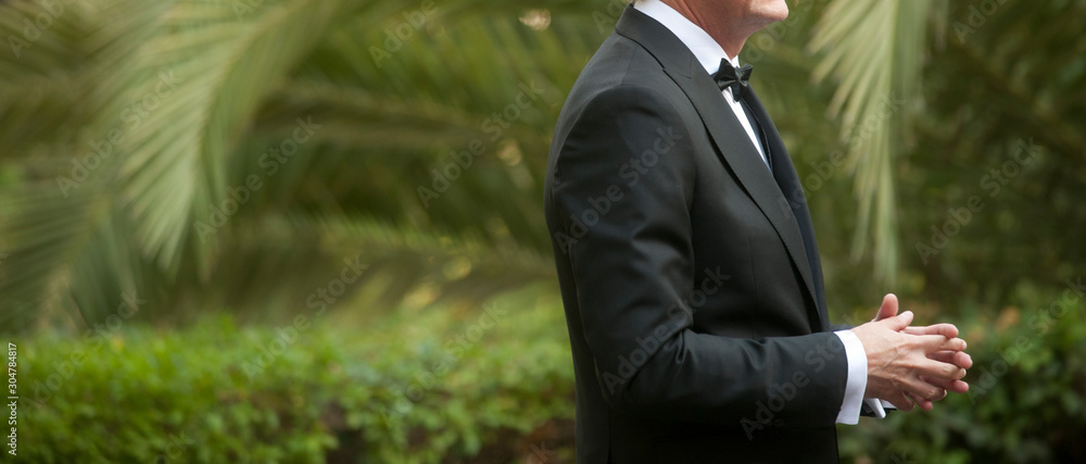 elegant man dressed in tuxedo for fantastic garden wedding in the background predominantly green elegant man dressed in tuxedo for fantastic garden wedding in the background predominantly green