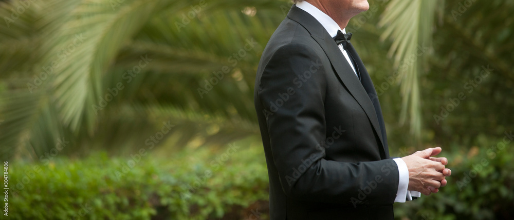 elegant man dressed in tuxedo for fantastic garden wedding in the background predominantly green elegant man dressed in tuxedo for fantastic garden wedding in the background predominantly green