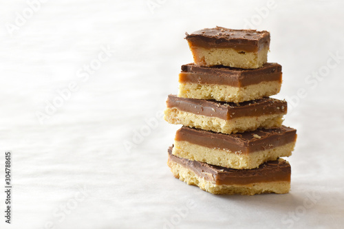 Fotografi Millionaire's shortbread with chocolate and caramel on a parchment paper with copy space on the left side