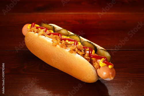 Fototapeta Danish hot dog with pickled cucumbers, fried onions, ketchup and mustard