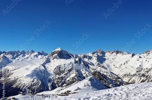 Panoramic view of snowy mountains peaks in the clouds blue sky Caucasus © Mokrousov Boris