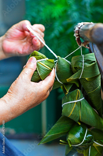Картината върху платно Two Hands Tighten String Over the Leaf to Make Zongzi, the Traditional Chinese R
