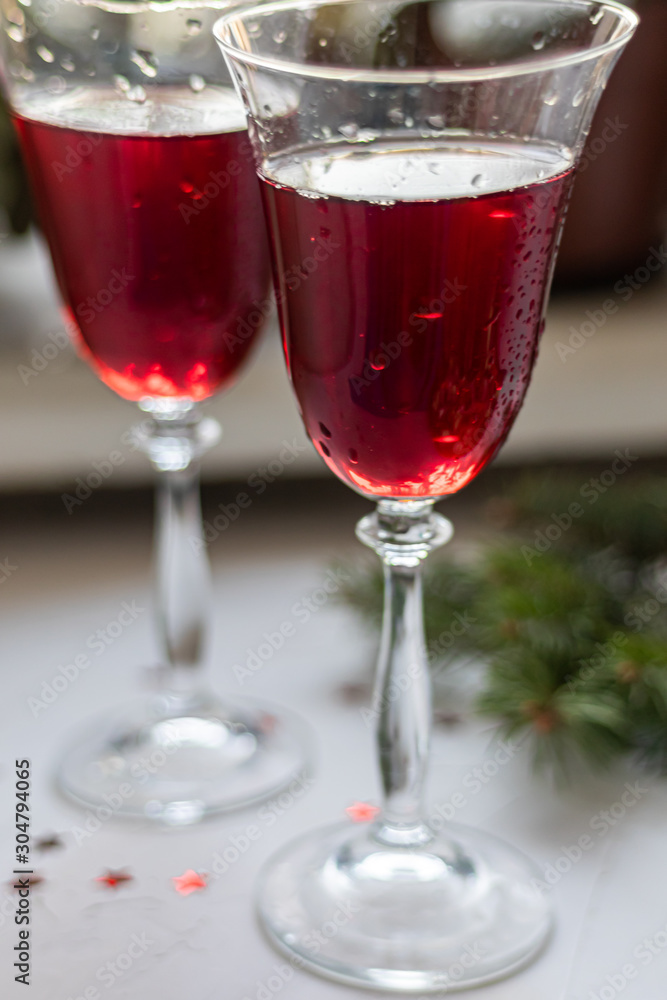 Red wine in transparent glasses. On a light background. Blurred background behind. Christmas tree branches. Copy space. 