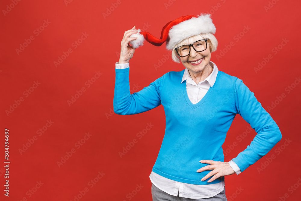 Senior aged grey-haired woman wearing Christmas Santa hat over isolated red background very happy and excited, having fun, smiling.