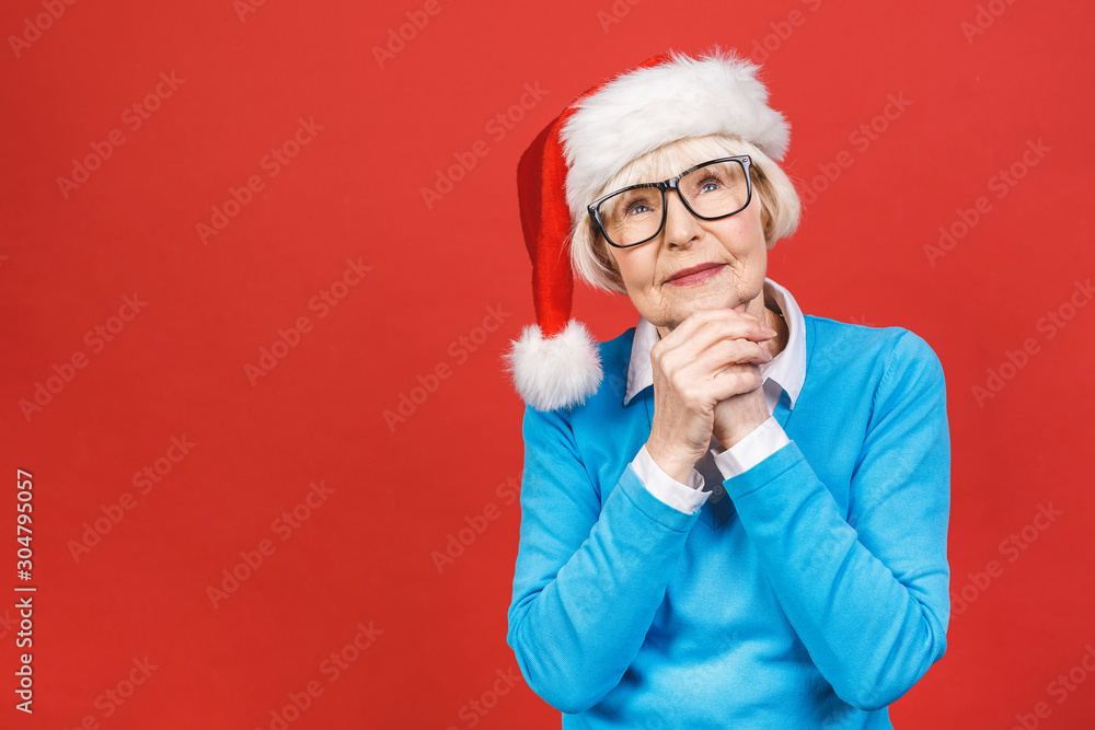 Senior aged grey-haired woman wearing Christmas Santa hat over isolated red background very happy and excited, having fun, smiling. Senior aged grey-haired woman wearing Christmas Santa hat over isolated red background very happy and excited, having fun, smiling.