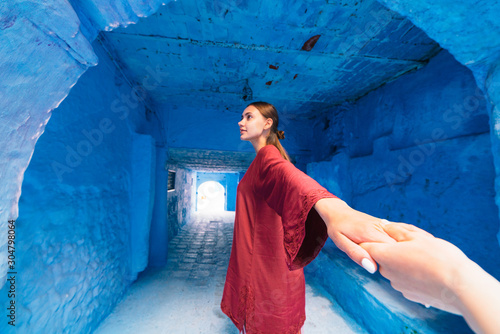 the hand entering the frame holds the hand of the girl leaving the tunnel in the blue city. Morocco © nelen.ru