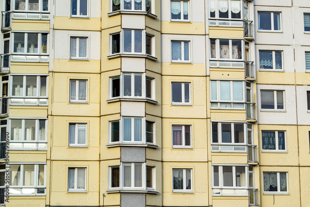 Bottom view of a tall apartment building with various shades of beige walls.