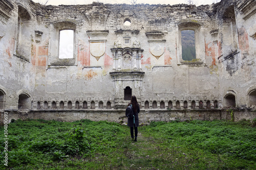 Young slender girl with long blond hair examines the ruins of an ancient synagogue. Traveler with a backpack. Moldova. Rashkov. photo