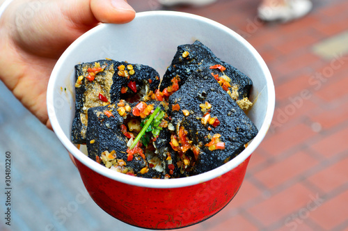 Tableau sur toile A Hand Hoiding A Box with Black Deep Fried Stinky Tofu