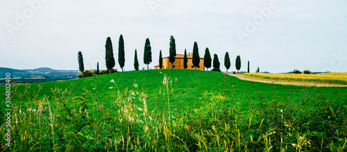 Tuscany beautiful spring landscape. Agricultural area with fields and farmhouse. Countryside farm  cypresses trees  green field  sun light and cloud  Italy  Europe.