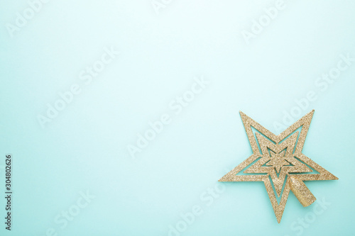 Golden glittering star on mint background with copy space