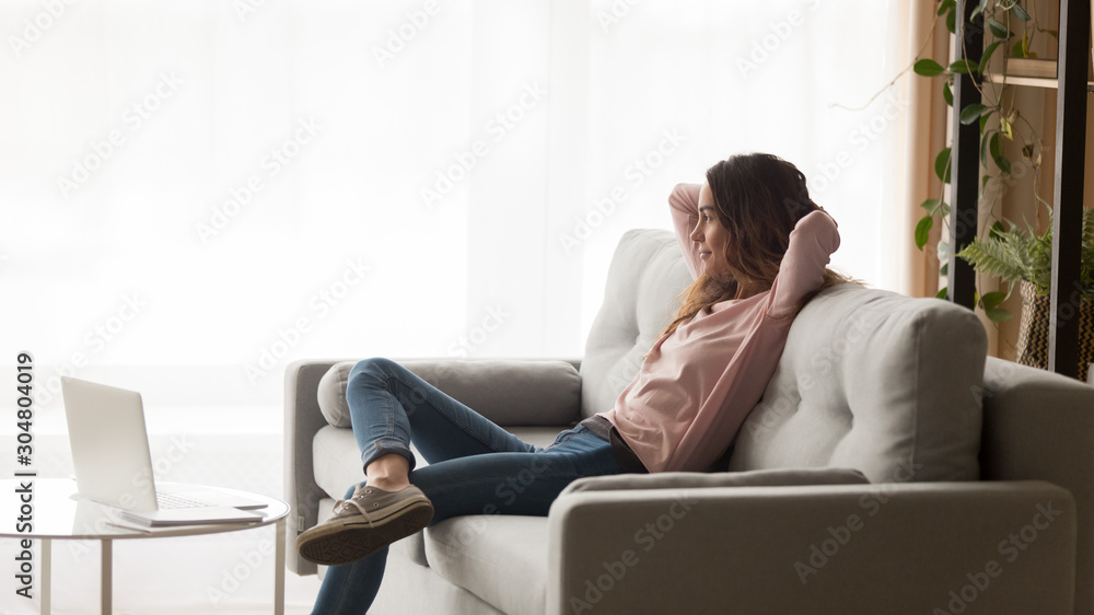 Happy woman relax on couch dreaming looking in window Happy woman relax on couch dreaming looking in window