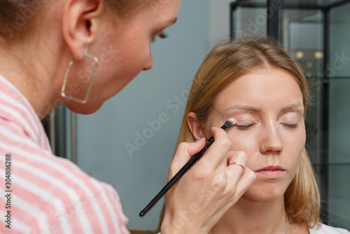 The process of creating makeup. Makeup artist working with a brush on the face of the model.